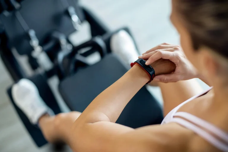 closeup sportswoman using fitness tracker while working out gym